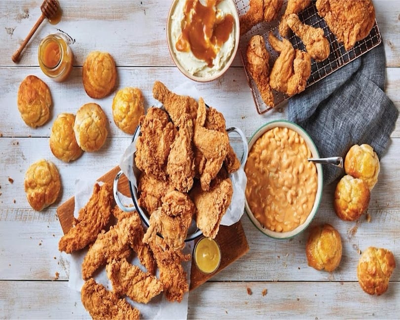 A feast of fried chicken, mashed potatoes with gravy, macaroni and cheese, biscuits, and honey.